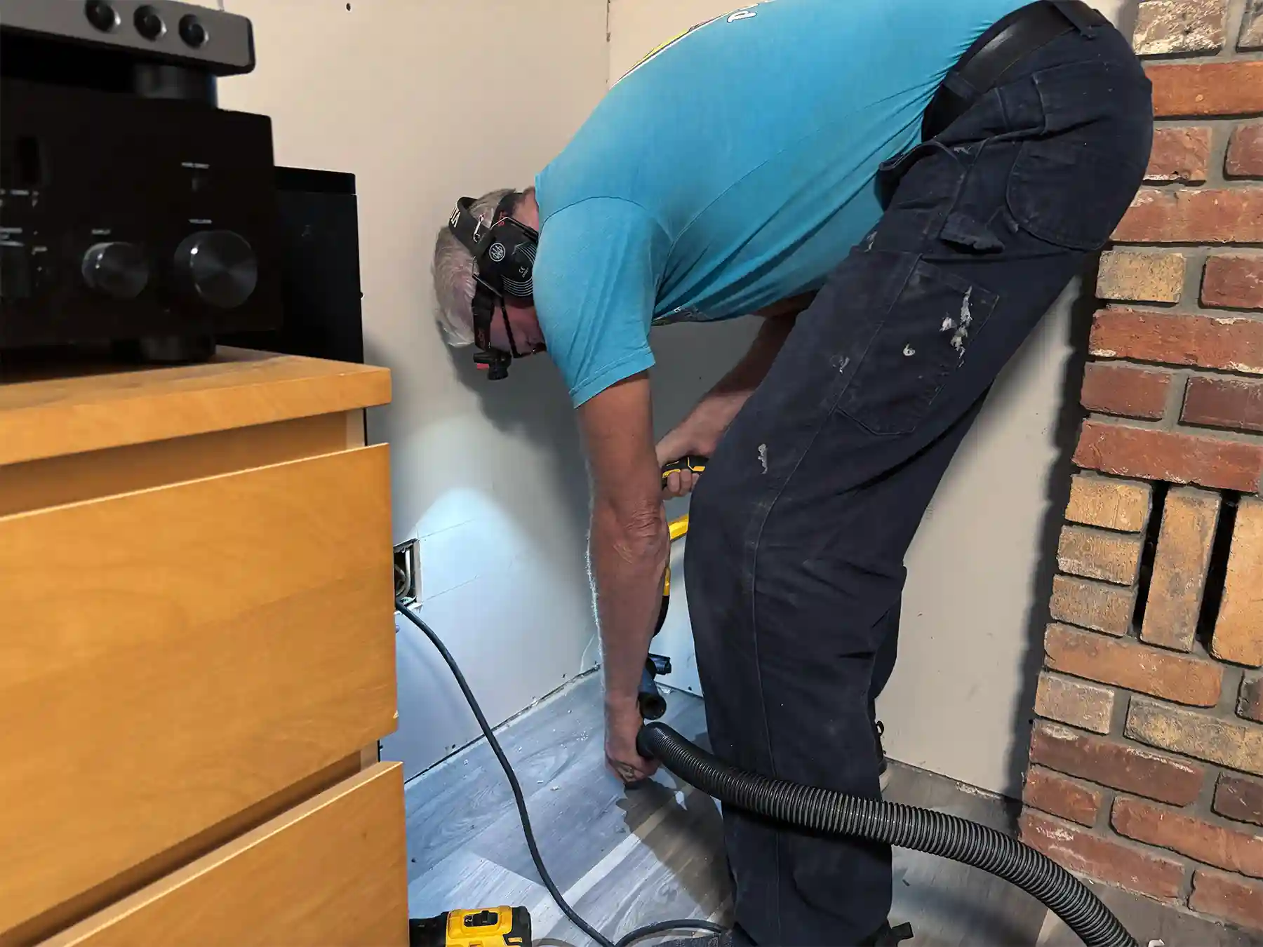 Greg Wheaton drilling radon testing holes in a basement.
